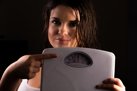 Young fit female trainer with scales の写真素材