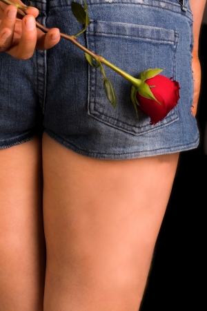 Young female holding rose behind backの写真素材