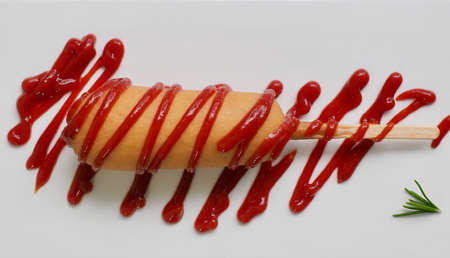Hot dog with ketchup on a white plateの写真素材