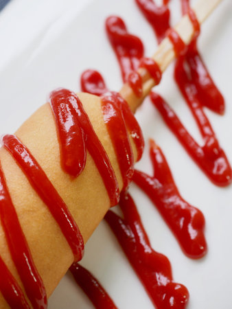 Hot dog with ketchup on a white plateの写真素材