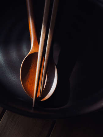 Wooden spoon and chopsticks on black porcelain plateの写真素材