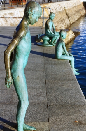 modern figures in bronze of child jumping into the sea from a pierの写真素材