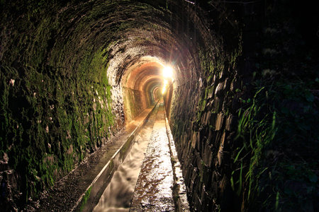 old tunnel moistened with water channel carved in the rockの写真素材