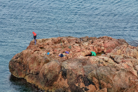 older man fishing on the shores of the sea with a caneの写真素材