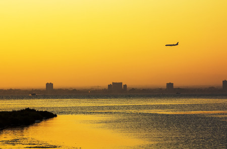 plane on the horizon during sunset by the seaの写真素材
