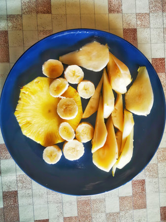 plate with pieces of fruit pineapple, pear bananaの写真素材