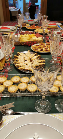 Table covered with a red and green checkered tablecloth for a Christmas atmosphere, with glassware and tableware, which adds a vibrant and cheerful touch to the spaceの写真素材