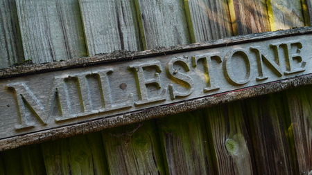 Weathered wooden milestone sign on slatted door/fence panelの写真素材