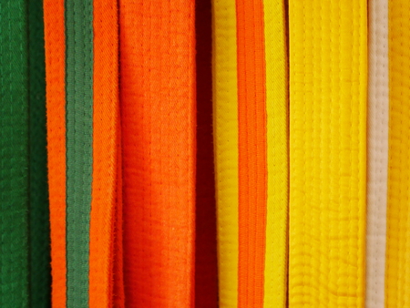 Closeup of martial arts belts for karate or kickboxing - white with yellow tag, yellow, yellow with orange tag, orange, orange with green tag, greenの写真素材