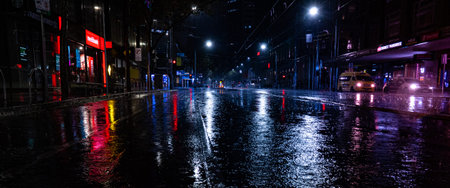 An empty rainy city street at night with lights reflecting in puddles in Melbourneの写真素材