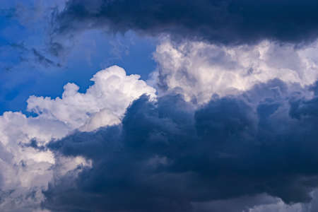 Dark grey and billowing white clouds against a blue skyの写真素材