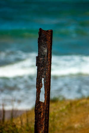 Rusted metal fence post with a coastal backgroundの写真素材
