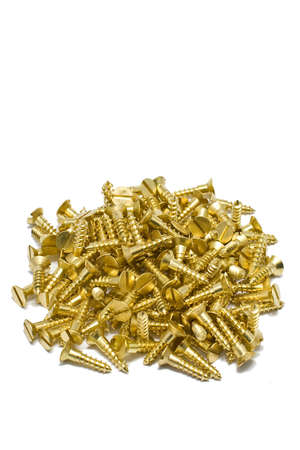 A pile of brass wood screws isolated on a white backgroundの写真素材