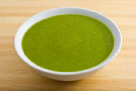 A bowl of broccoli soup on a wooden table の写真素材