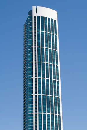A modern skyscraper with large galss windows against a blue sky の写真素材