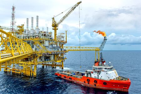 The shipping box is loaded from an offshore oil rig to the supply vessel at sunset.の写真素材