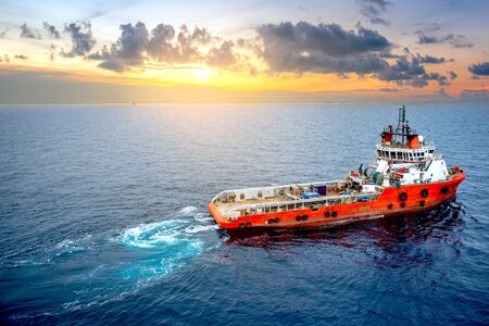 Supply boat offshore oil rig on loading operation with cloudy sky and blue ocean background.の写真素材
