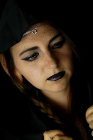 A young woman dressed as an elf with a black hooded robe and long hair with pointed elf earsの写真素材