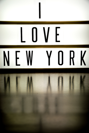 A light up board displays the phrase I LOVE NEW YORK reflected on woodの写真素材