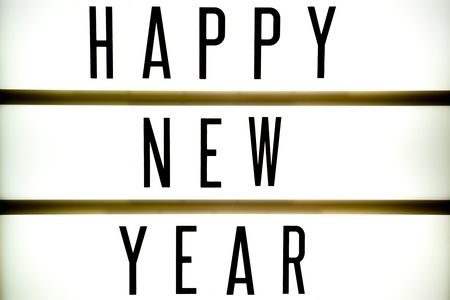 A light up board displays the phrase HAPPY NEW YEAR reflected on woodの写真素材