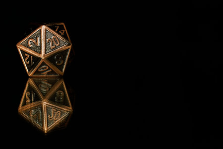 A twenty sided  polyhedral die on a mirrored surface. These type of dice are used for role playing...