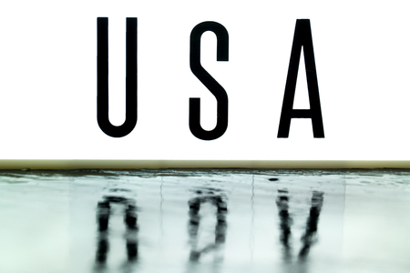 A light up board displays the phrase USA reflected on wet slateの写真素材