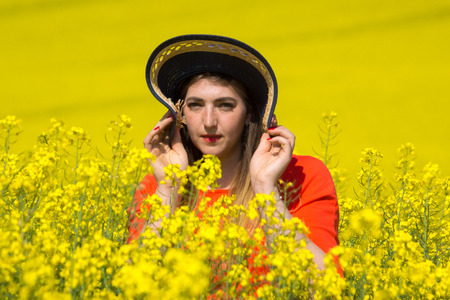 A young woman  wearing a red dress in the yellow fields of rapeseed.の写真素材