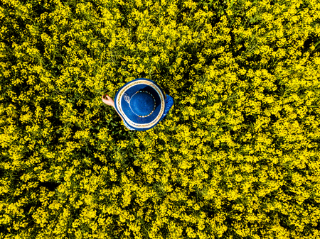 A young woman  wearing a blue dress in the yellow fields of rapeseed.の写真素材