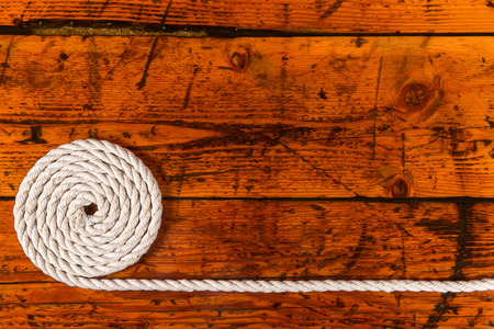 Coiled, white rope on a highly textured wooden background.  Copy space on right.  Nautical theme.の写真素材