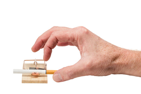 Handing reaching for cigarette in a mousetrap.  Studio closeup isolated on white background.の写真素材