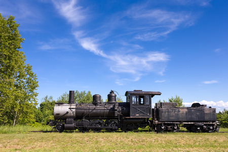 Dramatic view of an old steam train engine.  Abandoned locomotive and coal car seen on the prairie with copy space in blue sky if needed.の写真素材