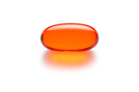 Orange gelatin capsule or pill isolated on a white background.  Medically themed studio macro with backlighting for extra pop.の写真素材