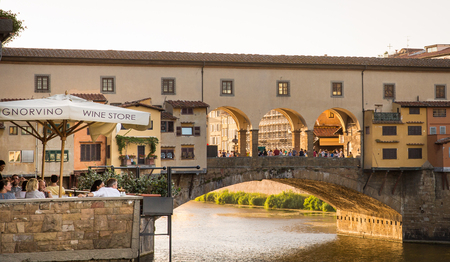 FLORENCE, ITALY - July 28, 2015:  Diners and tourists sip wine along the Arno River in the shadow of the Ponte Vecchio Bridge in Florence, Italy.  The Ponte Vecchio is a medieval bridge, famous for its shops and is a tourist destination spot in Florence.のeditorial素材