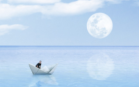 origami paper sailboat sailing on blue water concept artの写真素材