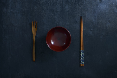 Black color wooden table top view. On the table are the Japanese wooden spoon, chopsticks, bowl .の写真素材