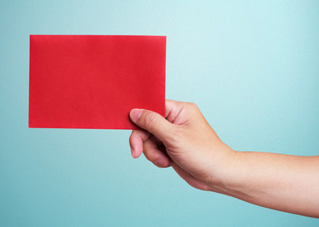 Hand holding chinese red envelope isolated over blue backgroundの写真素材