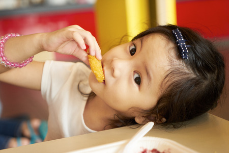Little girl eating fast foodの写真素材