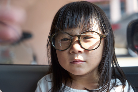 Adorable serious little girl and big funny glasses on her face. Toned image with shallow depth of fieldの写真素材