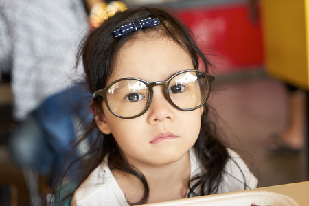 Adorable serious little girl and big funny glasses on her face. Toned image with shallow depth of fieldの写真素材