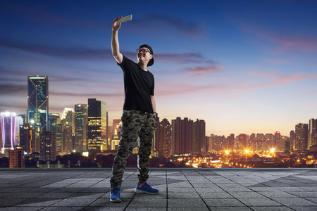 man taking selfie at rooftop on city skyline backgroundの写真素材