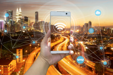 Hand holding white phone with city scape and internet network connection conceptの写真素材