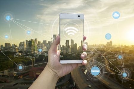 Hand holding white phone with city scape and internet network connection conceptの写真素材