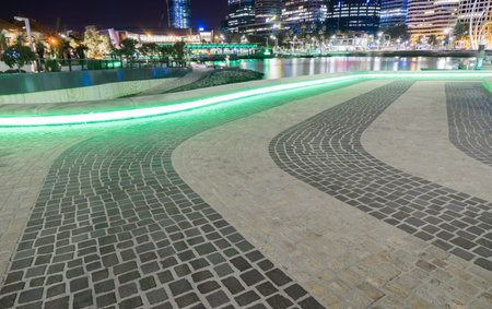 Green neon lights circulating underneath the stone seating reflecting on the stone pavement in Perth...