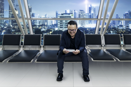Young smiling businessman sitting at conference room and using smart phoneの写真素材