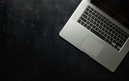 Wooden black office desk table with laptop . Top view