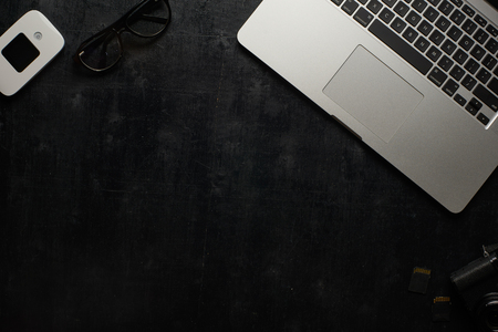 Wooden black office desk table with laptop, camera and other supplies . Top viewの写真素材