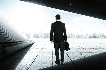 Businessman on the geometry design roof top balcony and looking at the city with skyscrapersの写真素材