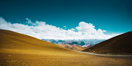 Beautiful scenery in Tibet with yellow hill  against blue and white clouds sky .の写真素材