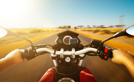 Biker driving a motorcycle rides along the country road , morning scene . First person angle view .の写真素材
