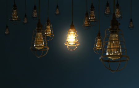 Hanging retro light bulbs decor on dark blue background with one isolated glowing .の写真素材